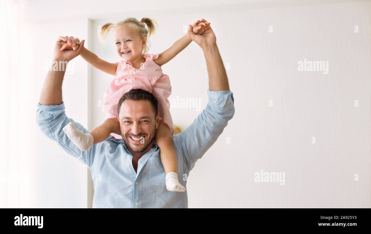 Millennial father riding his little daughter on shoulders Stock Photo