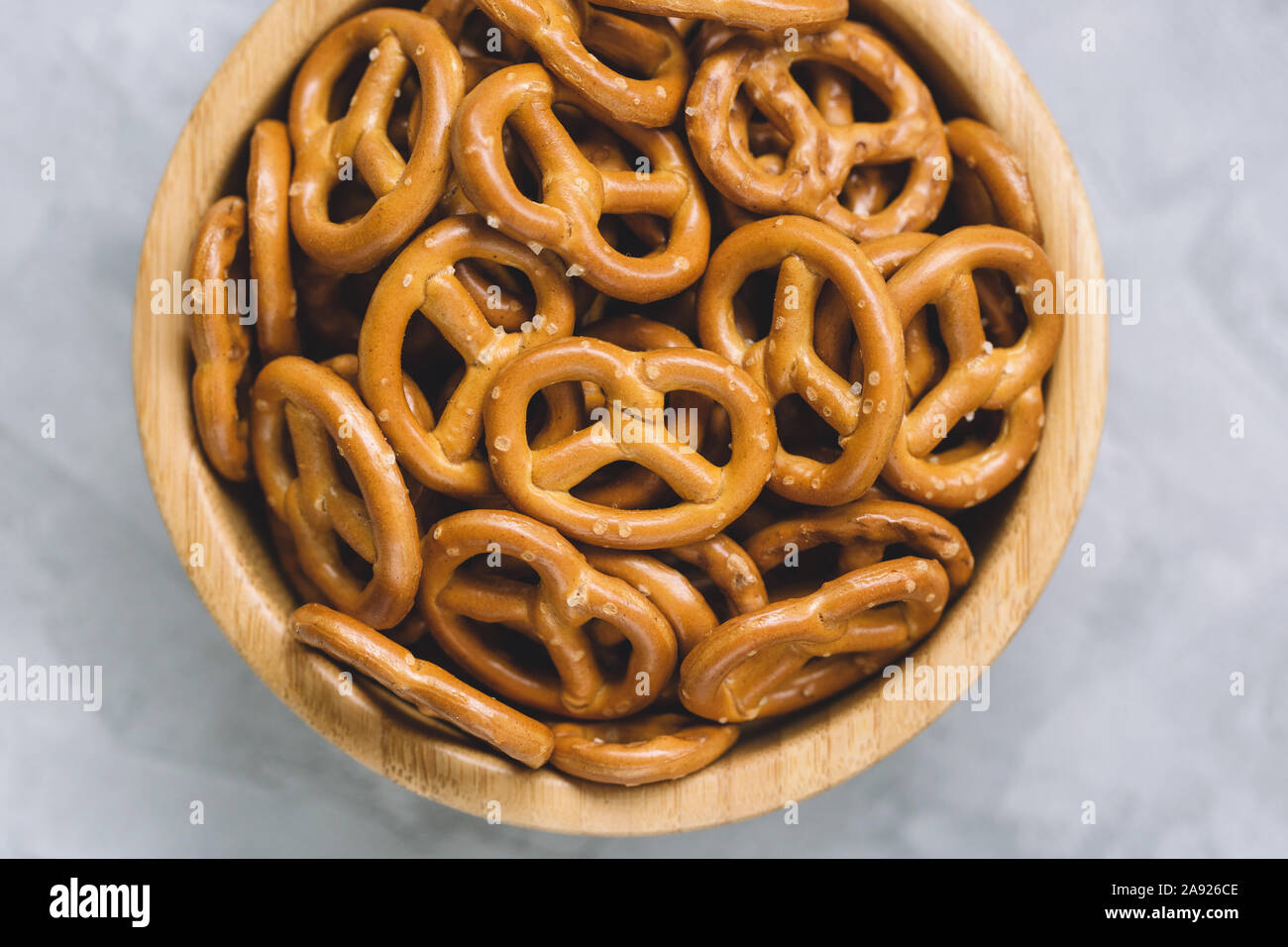 Traditional salty mini pretzels in wooden bowl on a gray backround. Stock Photo