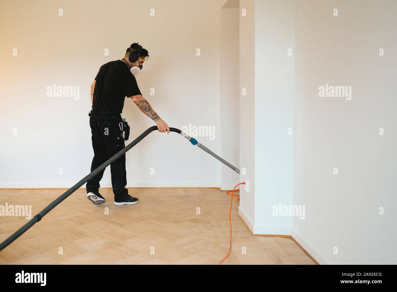 Man vacuuming parquet floor Stock Photo