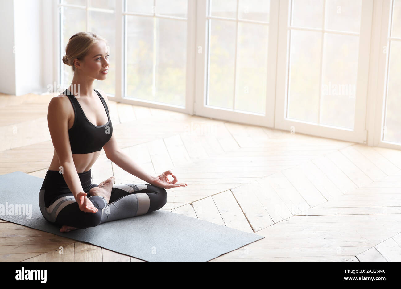 Happy sporty woman in lotus pose sitting on wooden floor Stock Photo ...