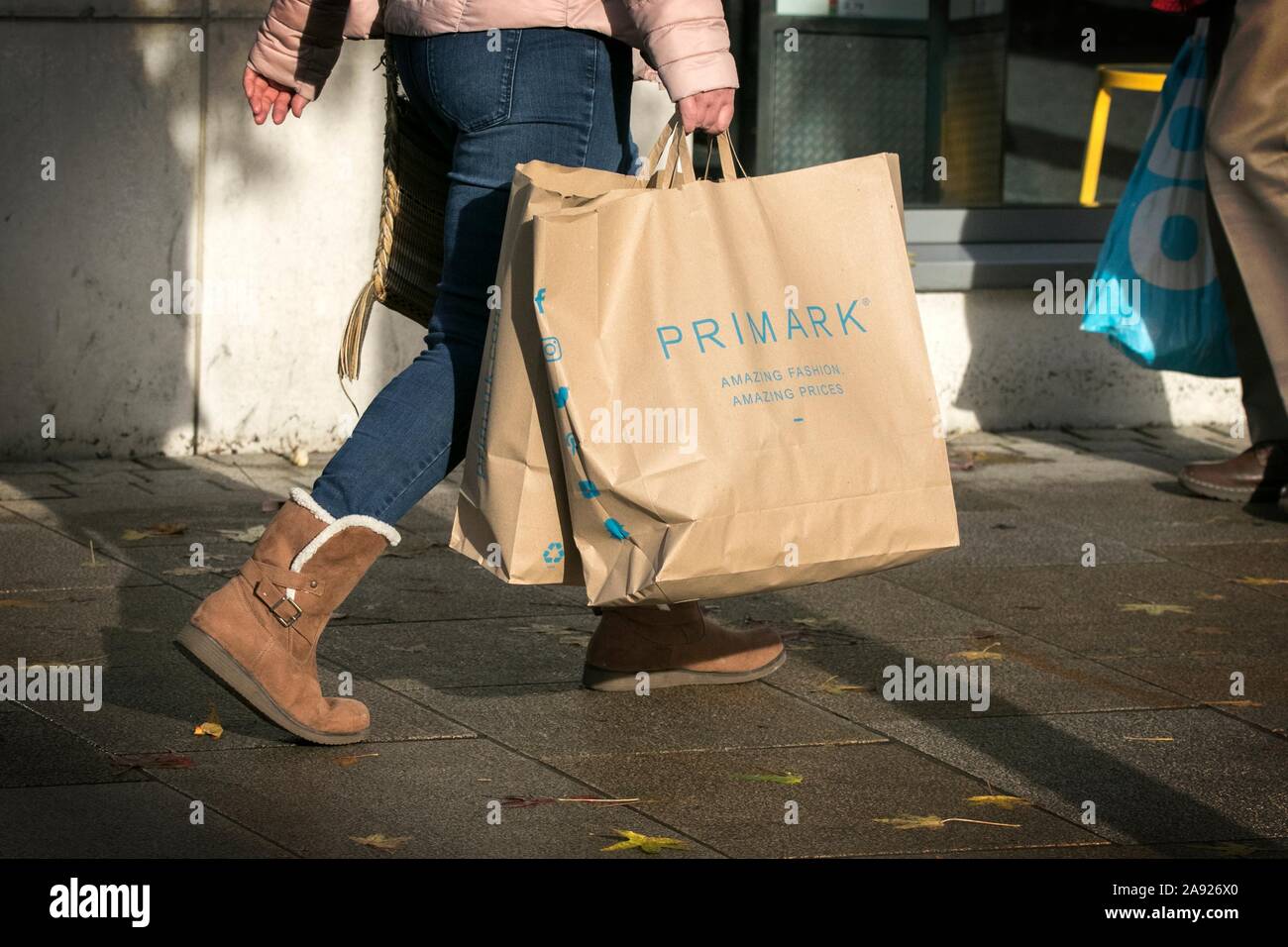 A woman carrying a Primark paper shopping carrier bag 100% recycled paper reusable supermarket Bags for Life Stock Photo