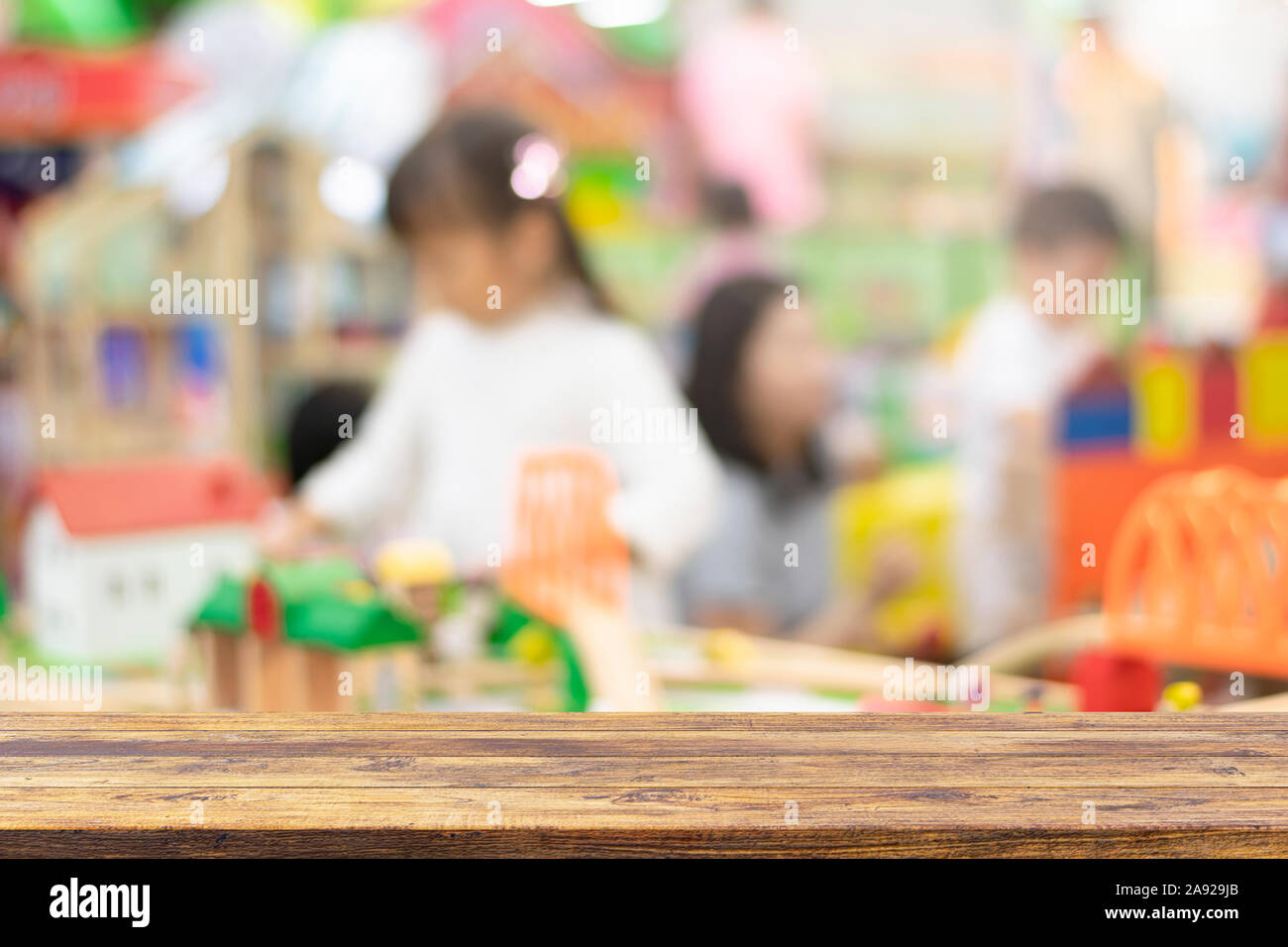 Empty wooden table top on blurred child playing in playground background . Ready used us display or montage products design backdrop. Stock Photo