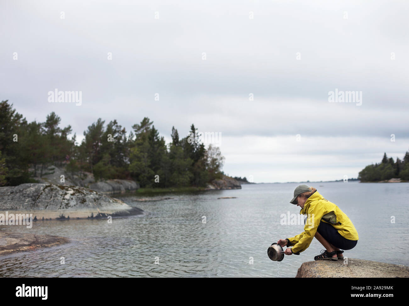 Woman doing the dishes at a lake Stock Photo