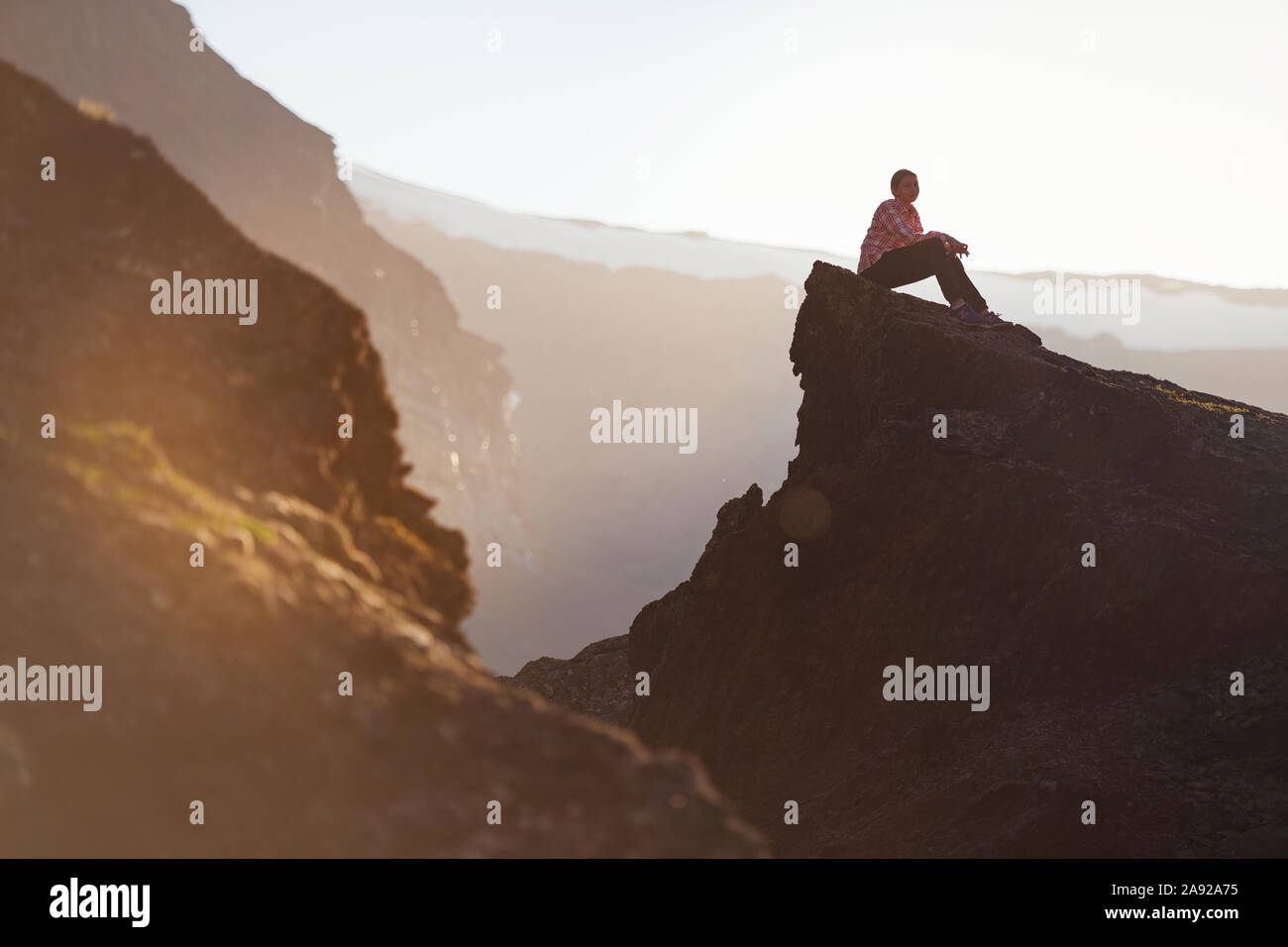 Girl sitting on top of mountain Stock Photo