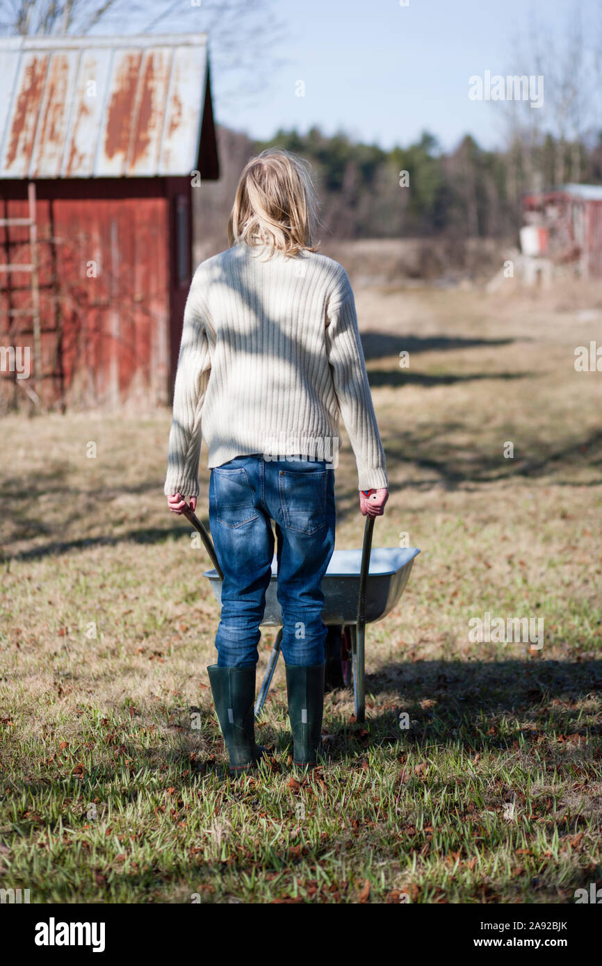 Woman pushing wheelbarrow Stock Photo