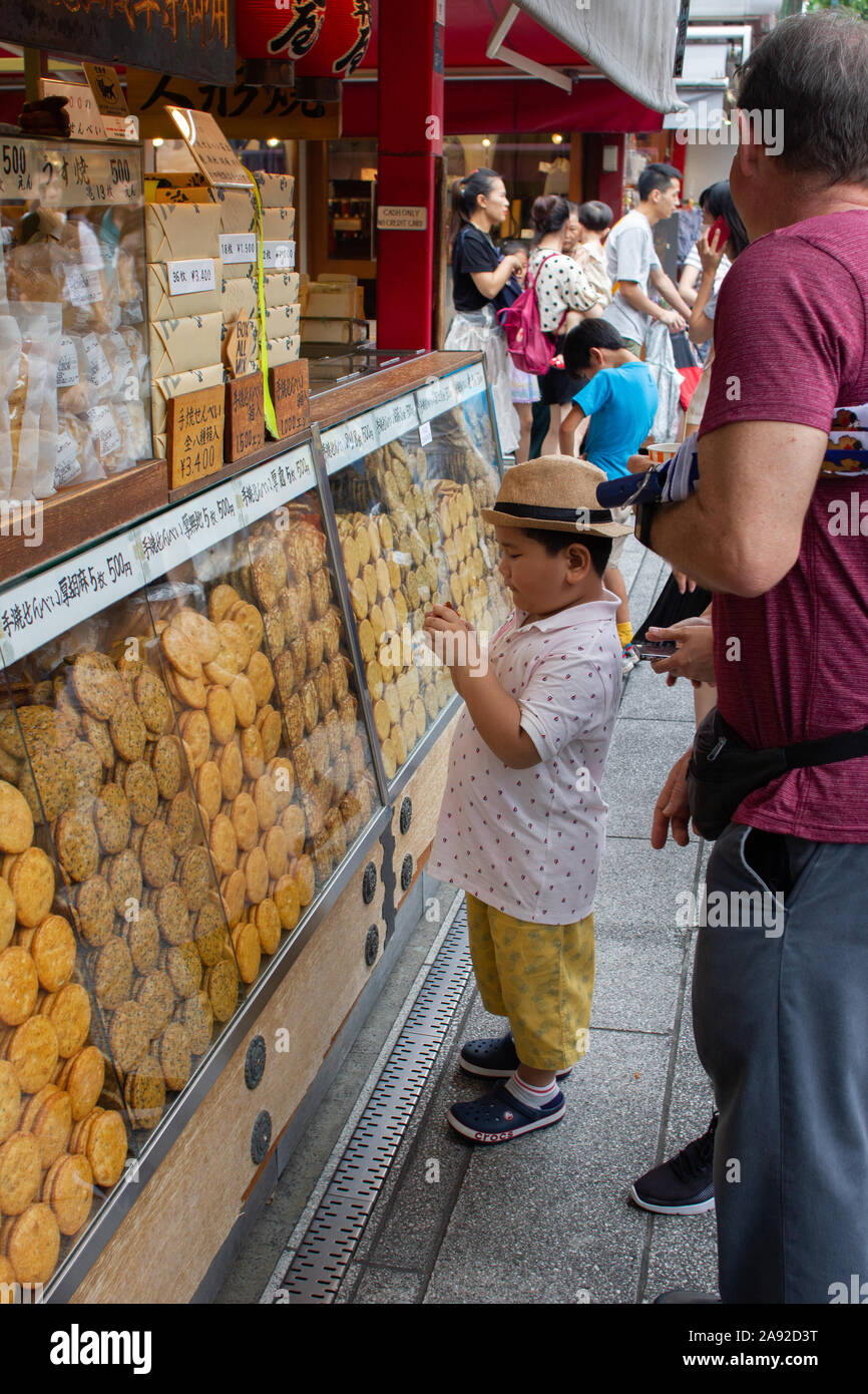 Boy buy rice crackers (senbei) in the shopping street (Nakamise) of Asakusa, Tokyo, Japan. Stock Photo