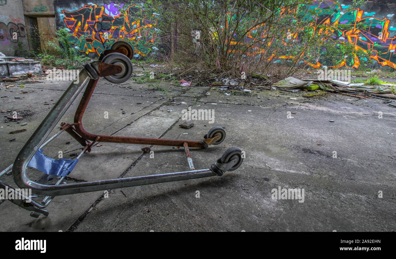 Close Up of Overturned Shopping Trolley/Cart in an Urban Environment Surrounded by Rubbish, Waste and Graffiti Stock Photo
