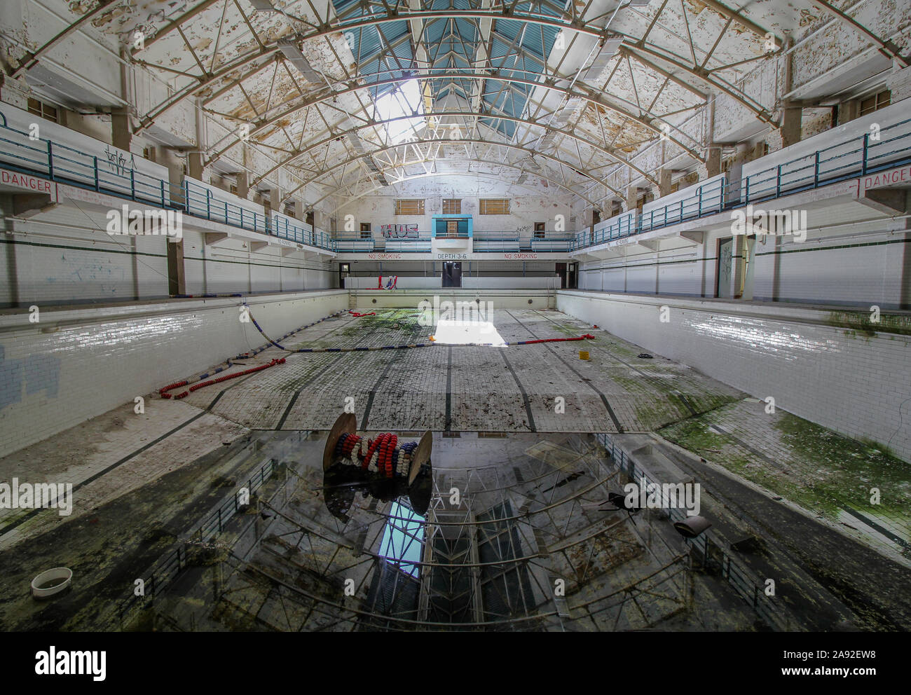 Full Shot of Abandoned Indoor Swimming Pool with Graffiti, Vandalism and Dirty Pool Water - Suffolk UK Stock Photo