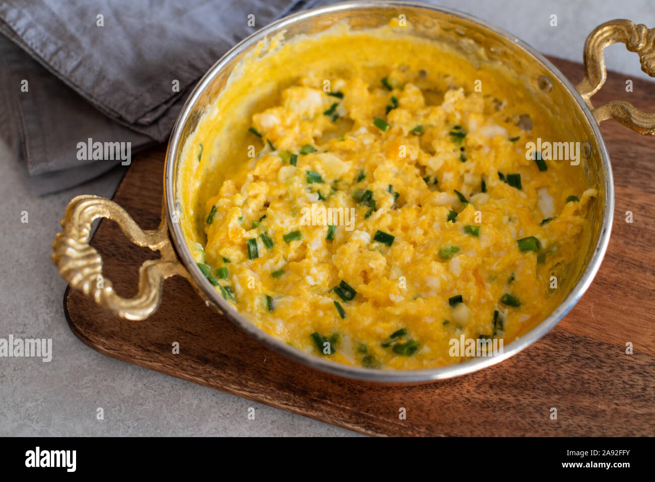 Scrambled eggs with cheese and spring onion. Breakfast is served. Stock Photo