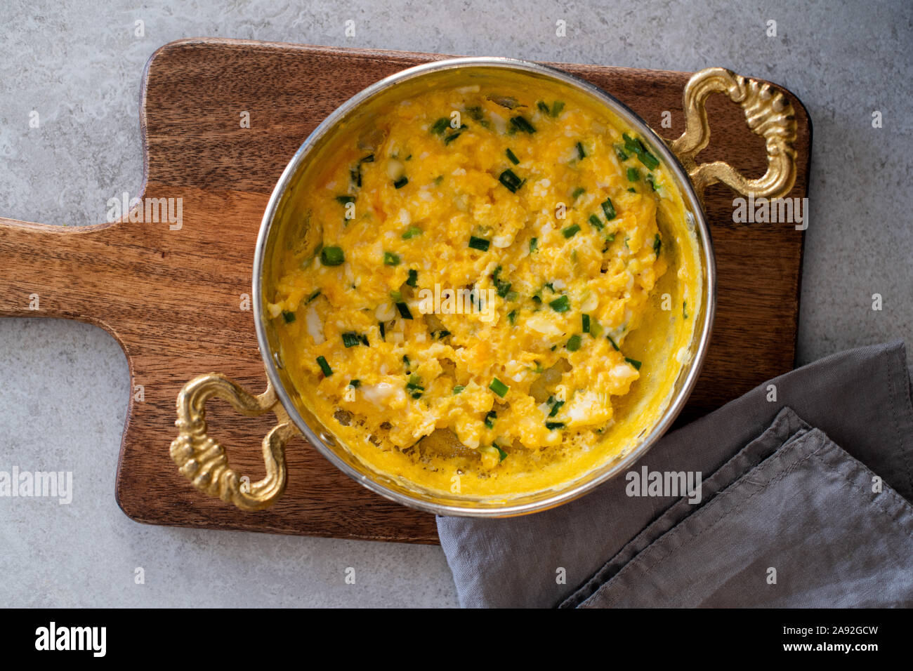 Scrambled eggs with cheese and spring onion. Breakfast is served. Stock Photo