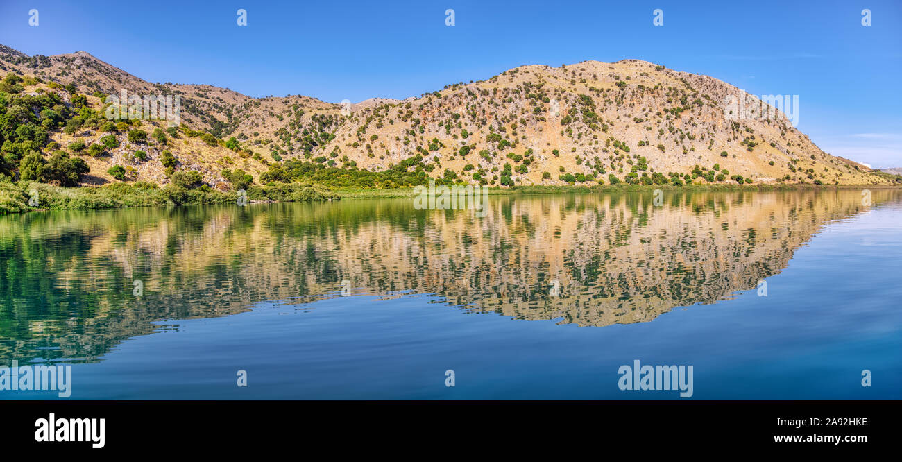 Panorama of the natural freshwater lake Kournas near Georgioupolis, the White Mountains reflected in the mirror-like water, island of Crete, Greece Stock Photo