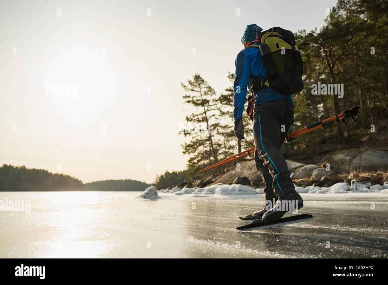 Man ice-skating on frozen lake Stock Photo