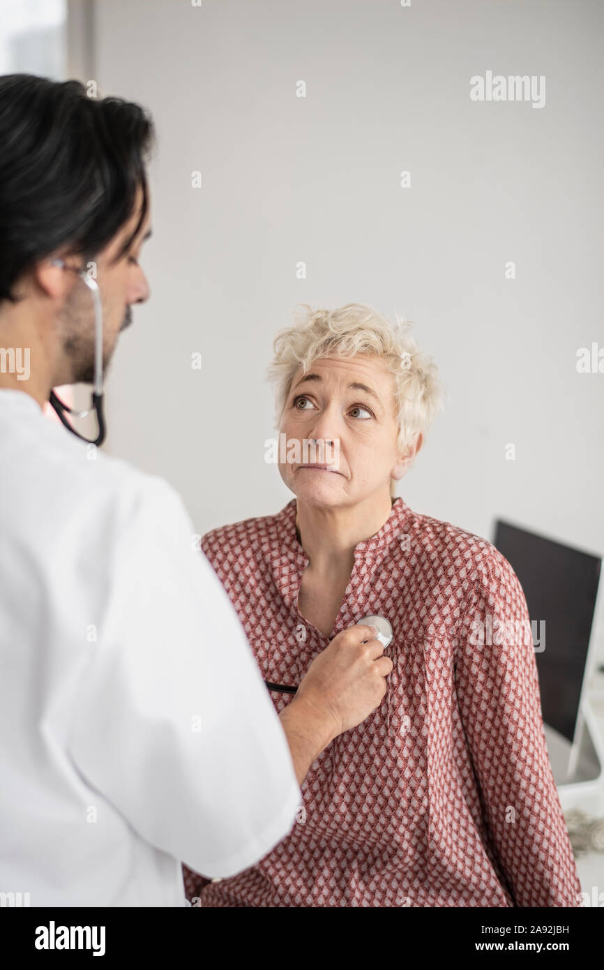 Doctor with stethoscope examining patient Stock Photo