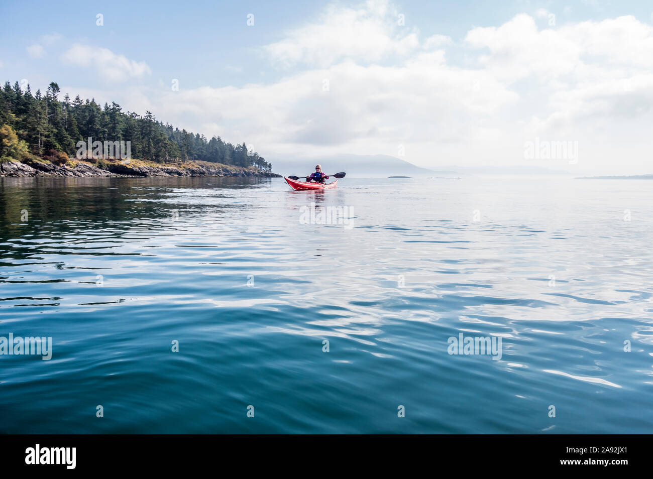 A woman sea kayaking in the morning off of Orcas Island in Rosario