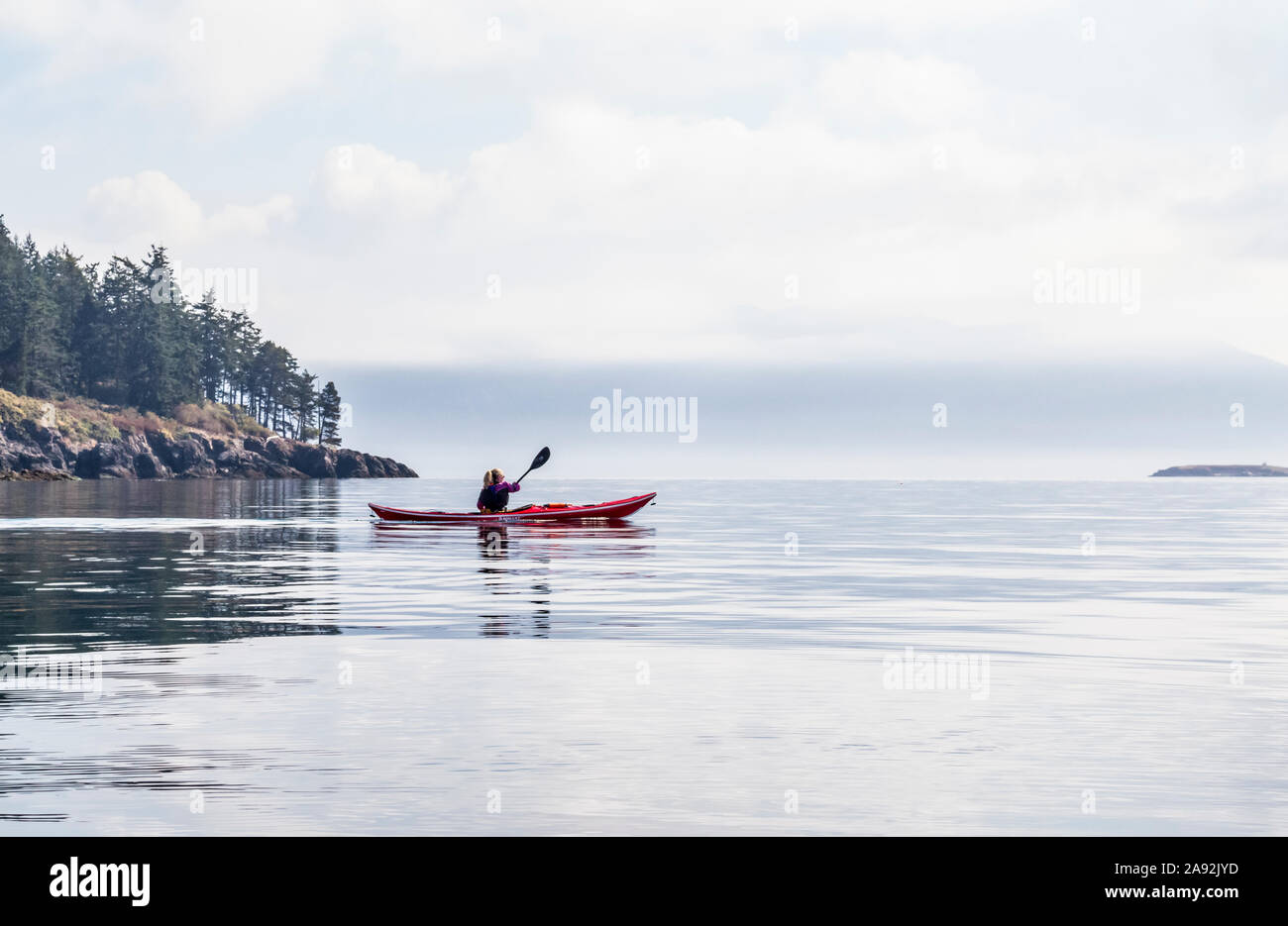 A woman sea kayaking in the morning off of Orcas Island in Rosario