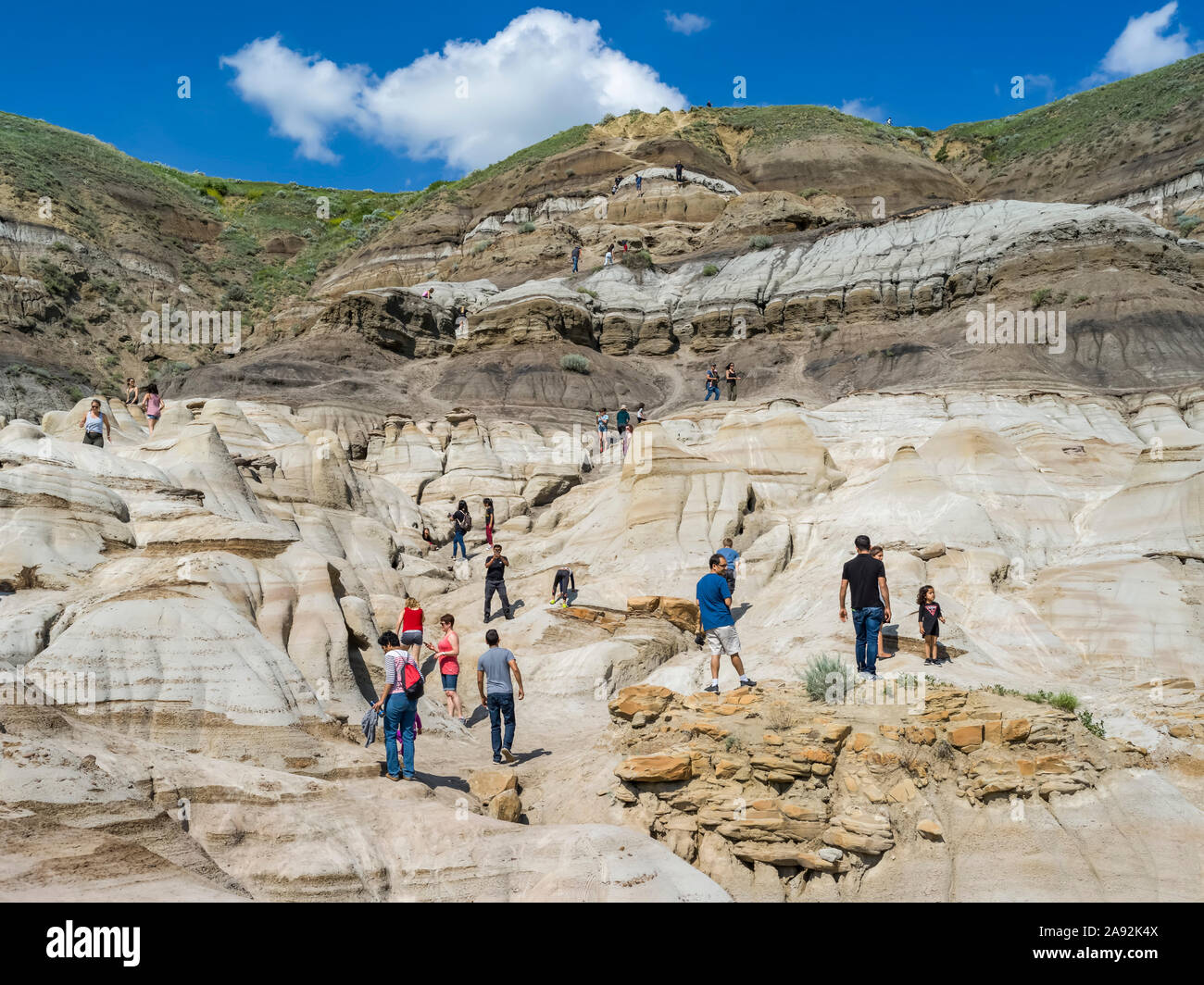 Tourists on Hoodoos Trail in the Canadian Badlands. Each hoodoo is a sandstone pillar resting on a thick base of shale that is capped by a large stone Stock Photo