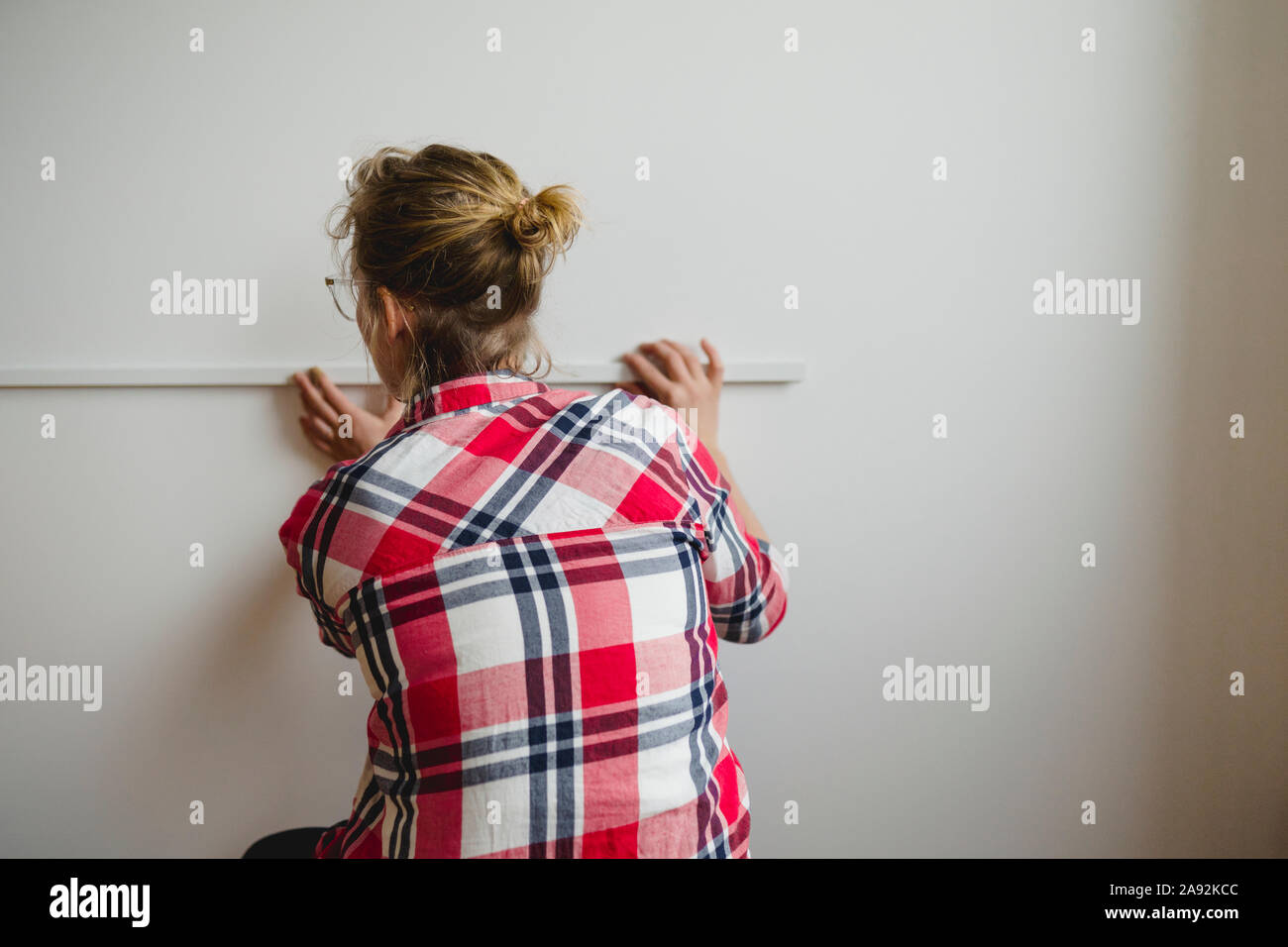 Woman measuring wall Stock Photo