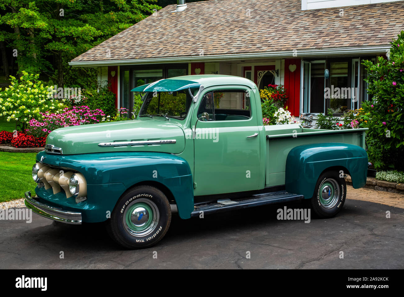 Vintage truck parked outside a house with blossoming flowers; Hudson, Quebec, Canada Stock Photo