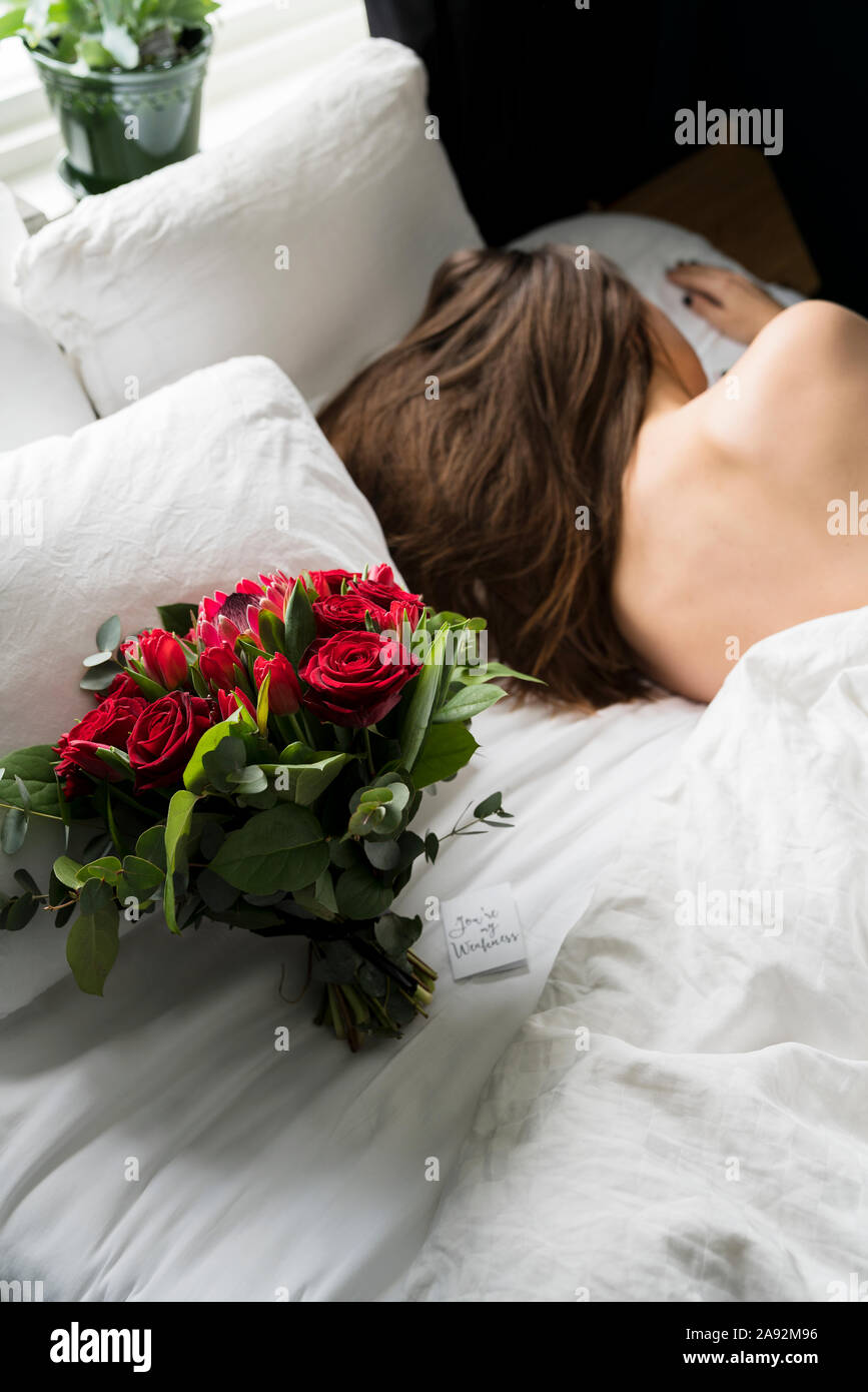 Bouquet of red roses on bed, sleeping woman on background Stock Photo ...