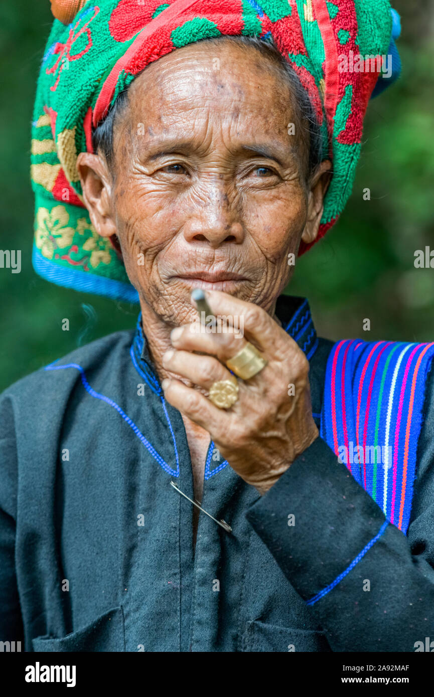 Burmese woman wearing a traditional head covering and smoking a cigarette; Yawngshwe, Shan State, Myanmar Stock Photo