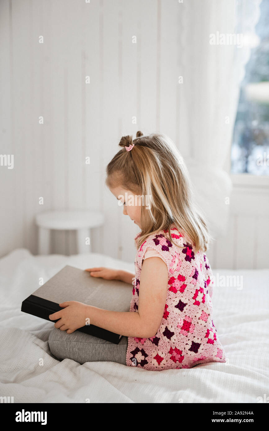 Girl on bed holding book Stock Photo