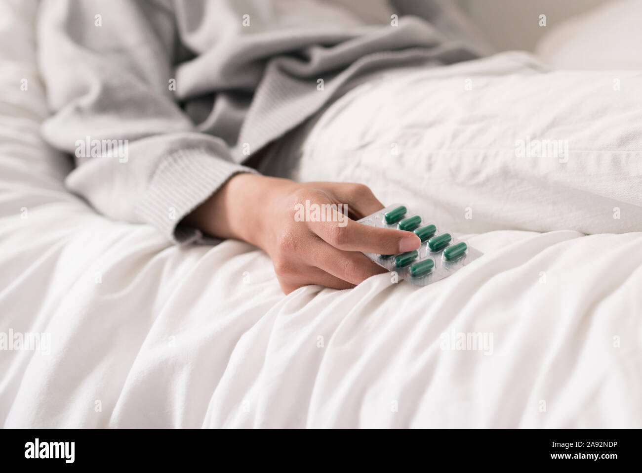 Man lying on bed and holding pills Stock Photo