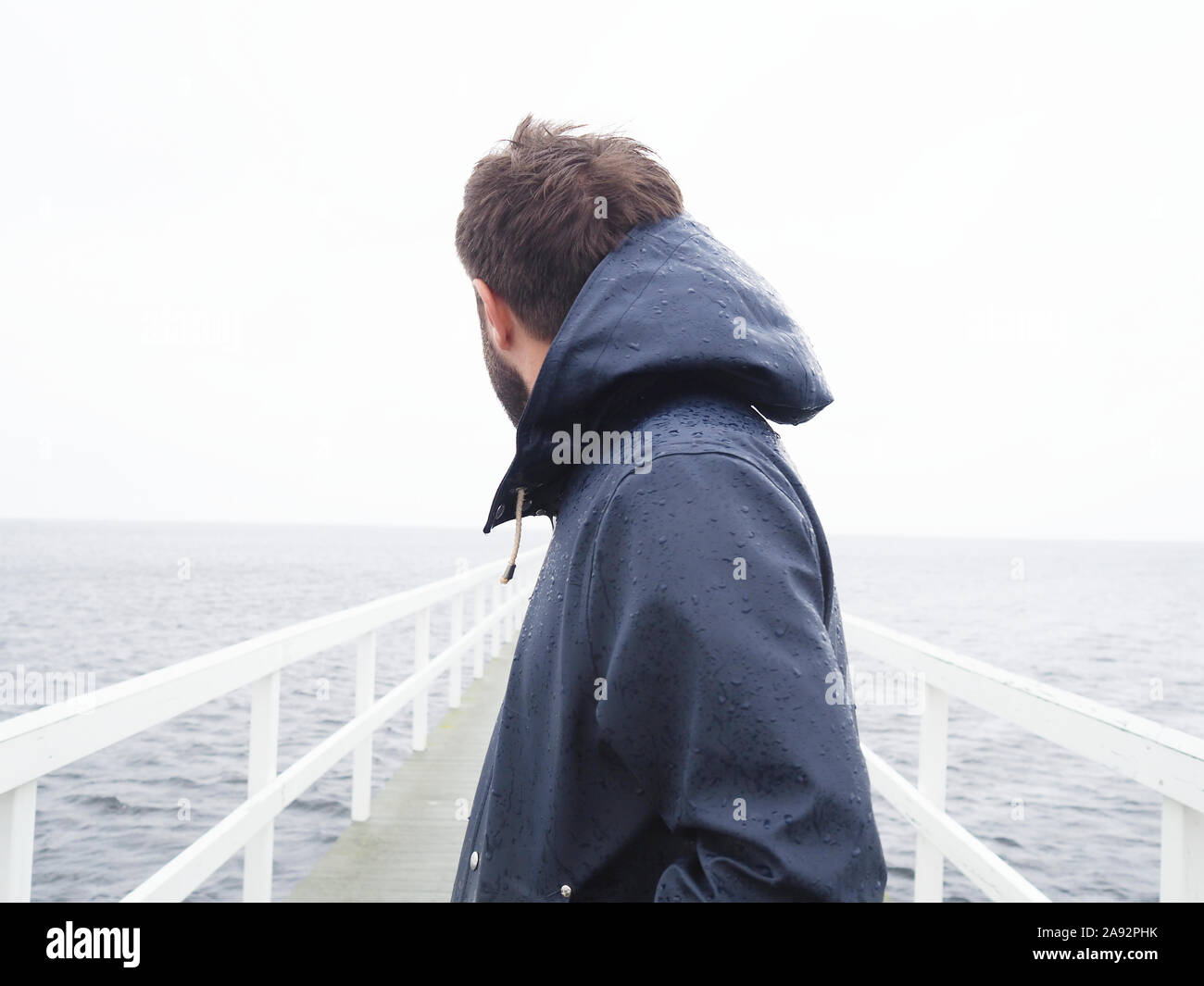 Man on jetty looking at sea Stock Photo