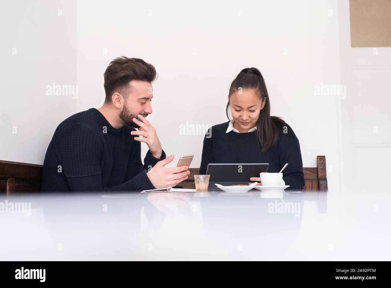 Couple in cafe using digital devices Stock Photo