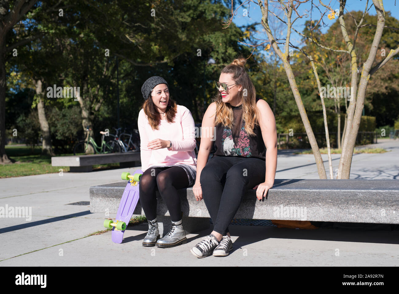 Female friends sitting on bench Stock Photo