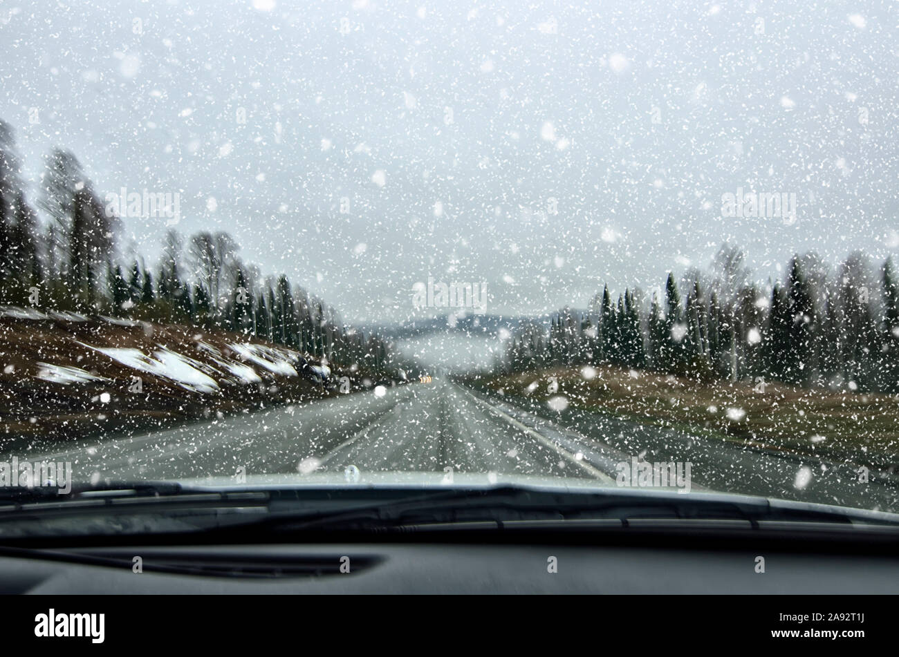 Vehicle safety in winter. Car driving in dangerous winter weather with poor visibility during snowfall and mist on the highway, concept for safety in Stock Photo