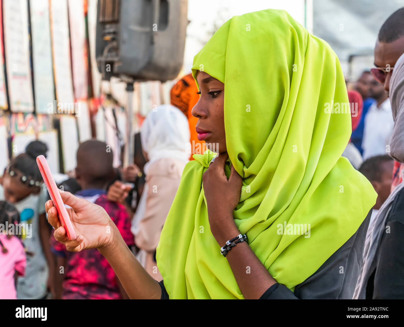Woman using her smart phone while attending the Muslim festival of Mawlid al-Nabi, which marks the birth of the Prophet Muhammad Stock Photo