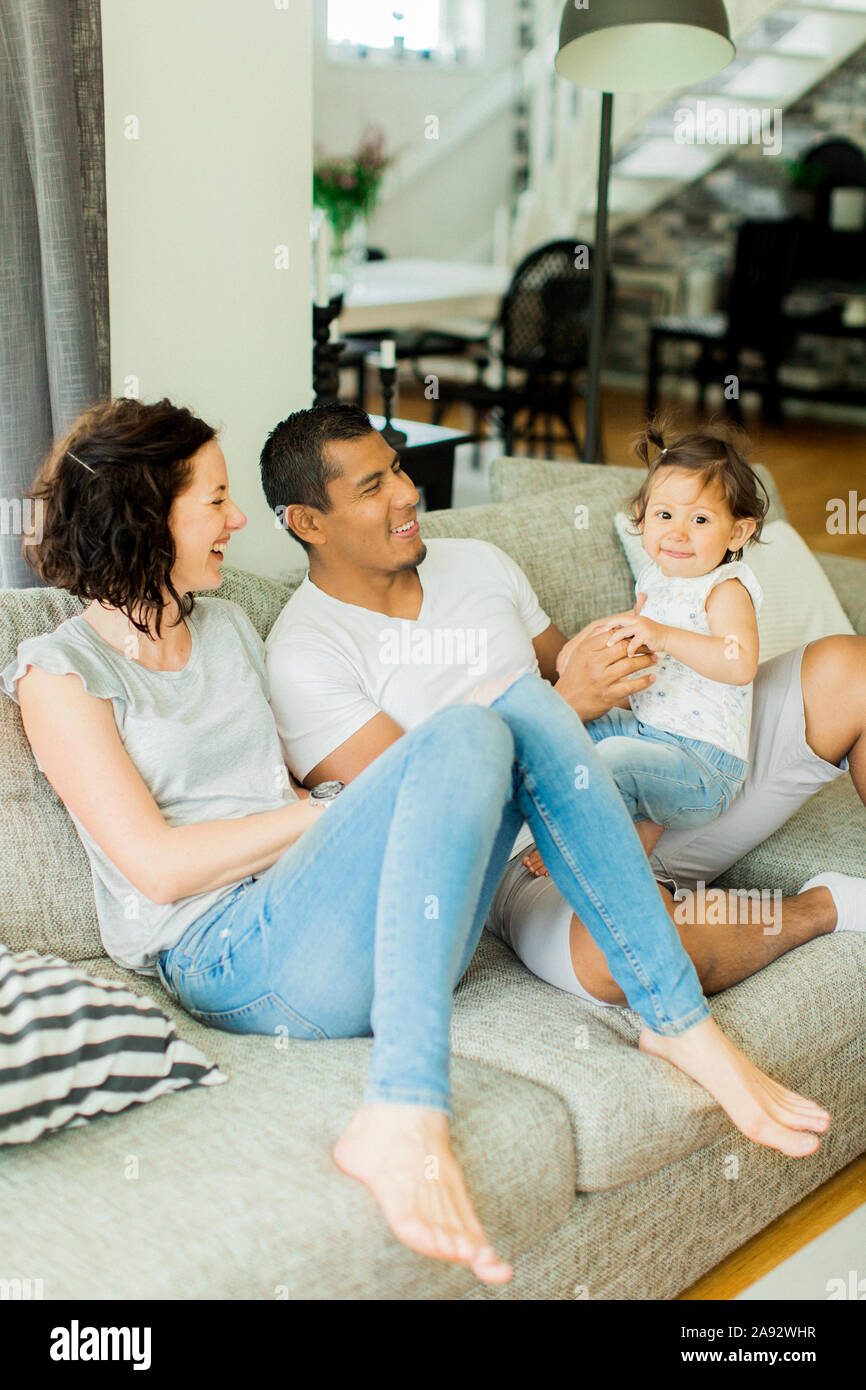 Parents with daughter sitting on sofa Stock Photo