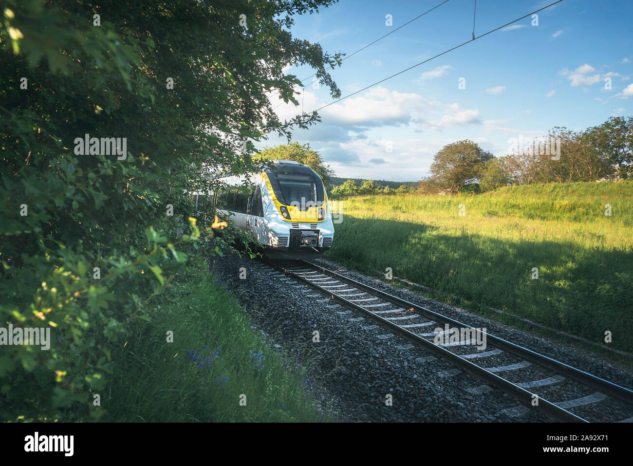 High-speed german train traveling through green nature landscape on sunny day. Train going through countryside scenery near Schwabisch Hall, Germany Stock Photo