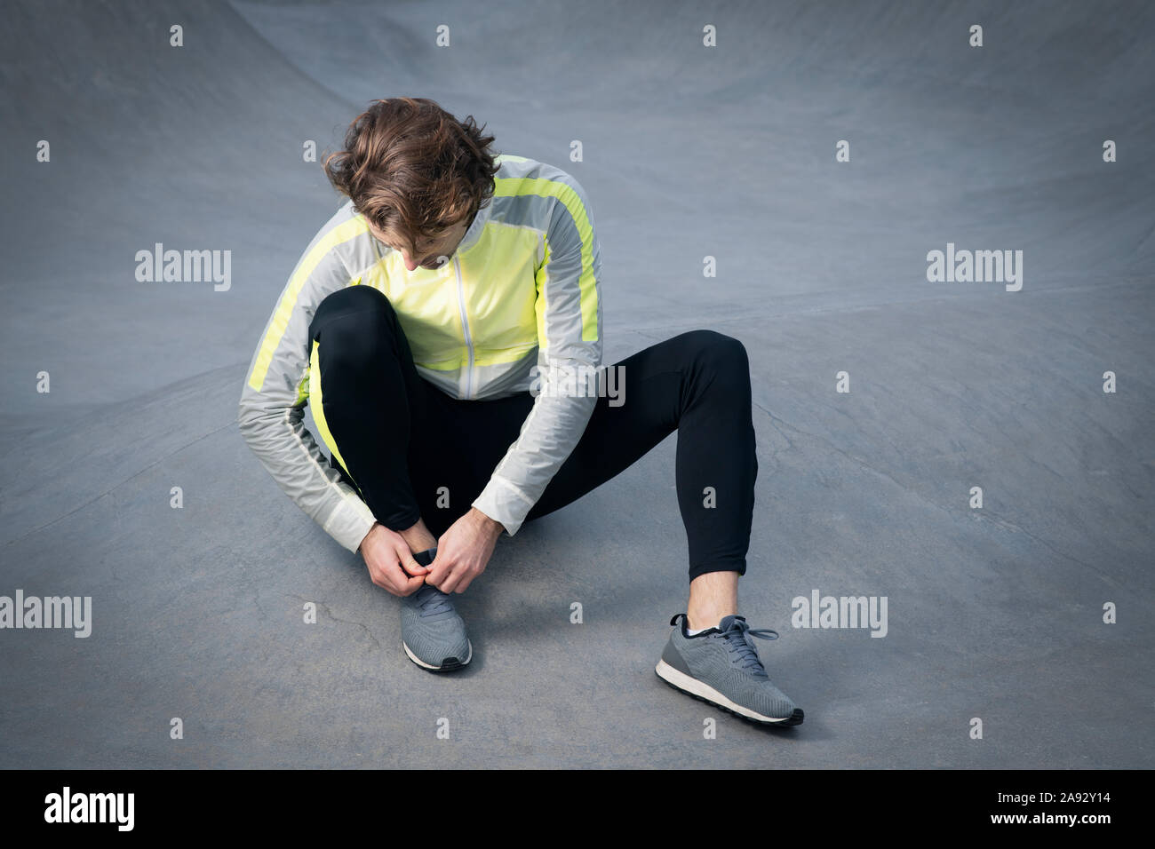 Man in sport clothes tying shoe Stock Photo