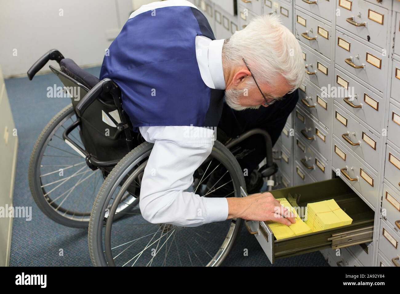 Man with Muscular Dystrophy in a wheelchair working in an office Stock
