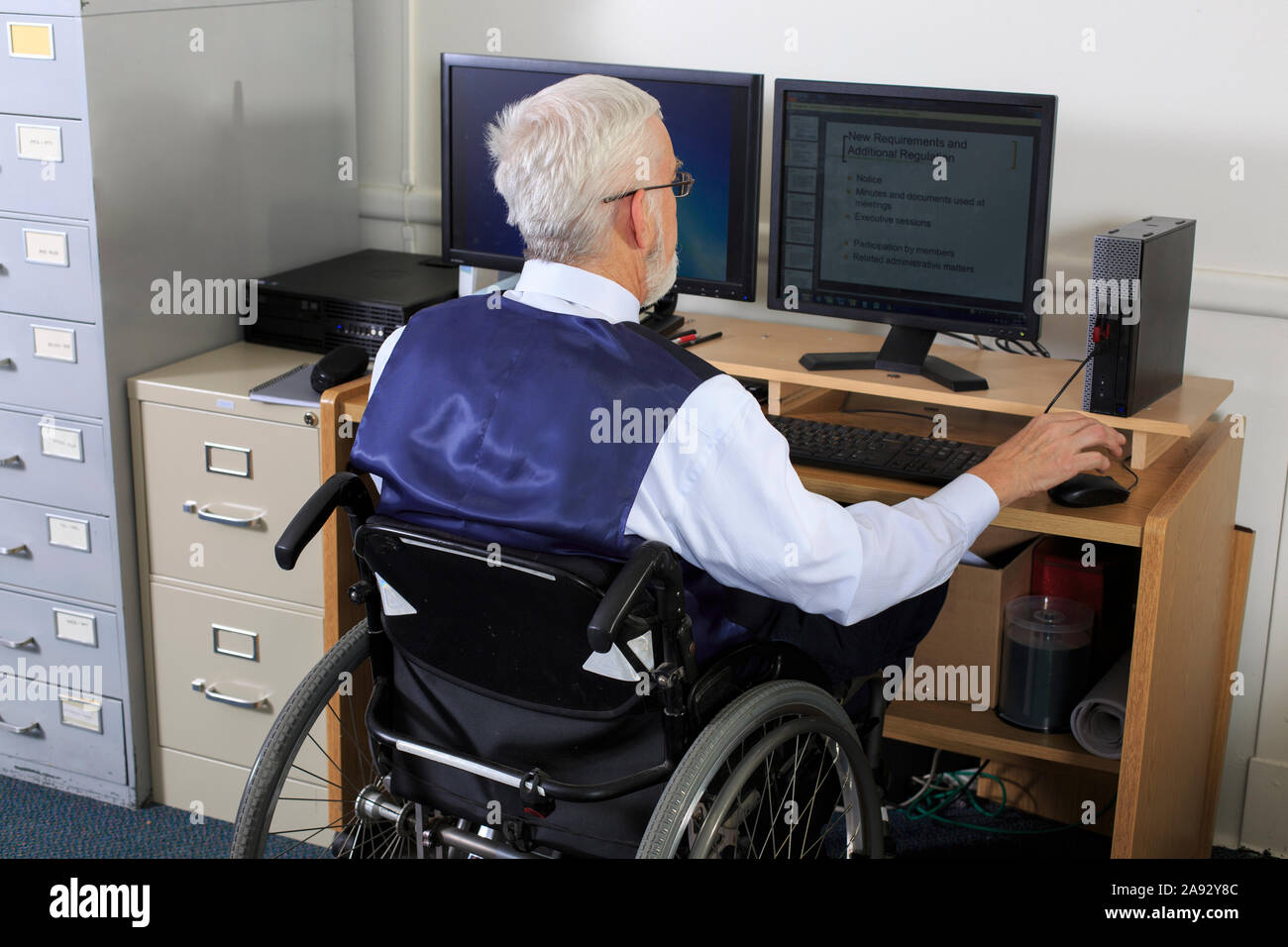 Man with Muscular Dystrophy in a wheelchair working in an office Stock