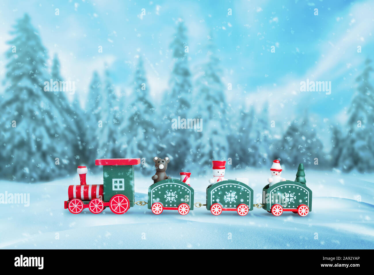 Cute train in the snow. Christmas, New Year background with a lot of snowflakes. Snow trees in background. Stock Photo