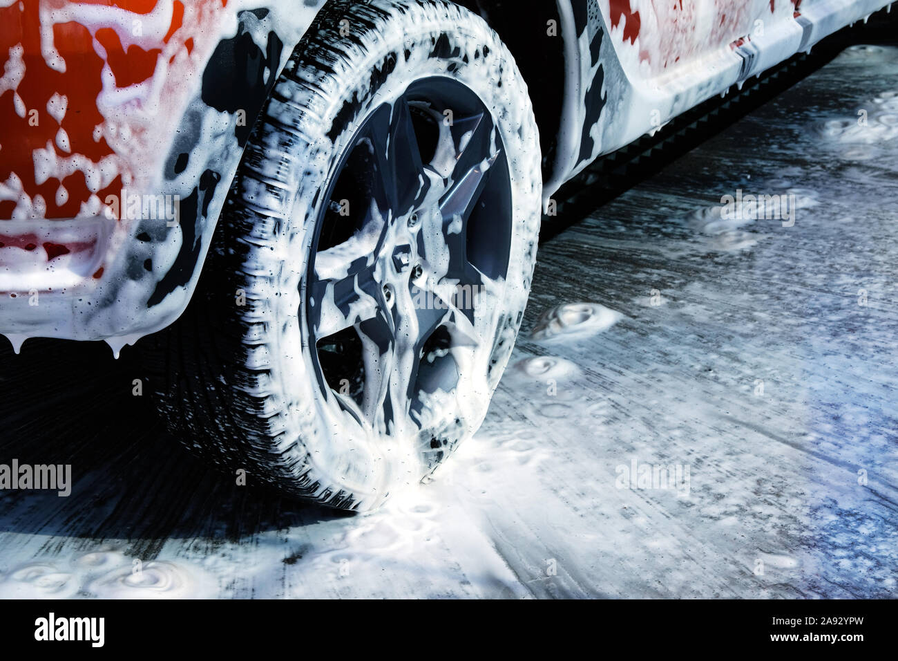 Car wheel close up. Car is cleaning with soap suds at self service car