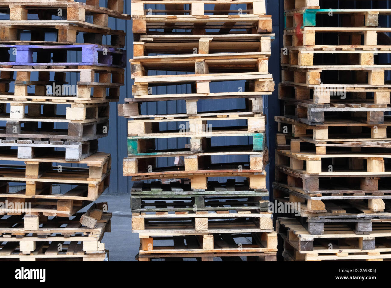 Pallets background. Stacks of colorful rough wooden pallets at warehouse in industrial yard. Cargo and shipping concept. Stock Photo