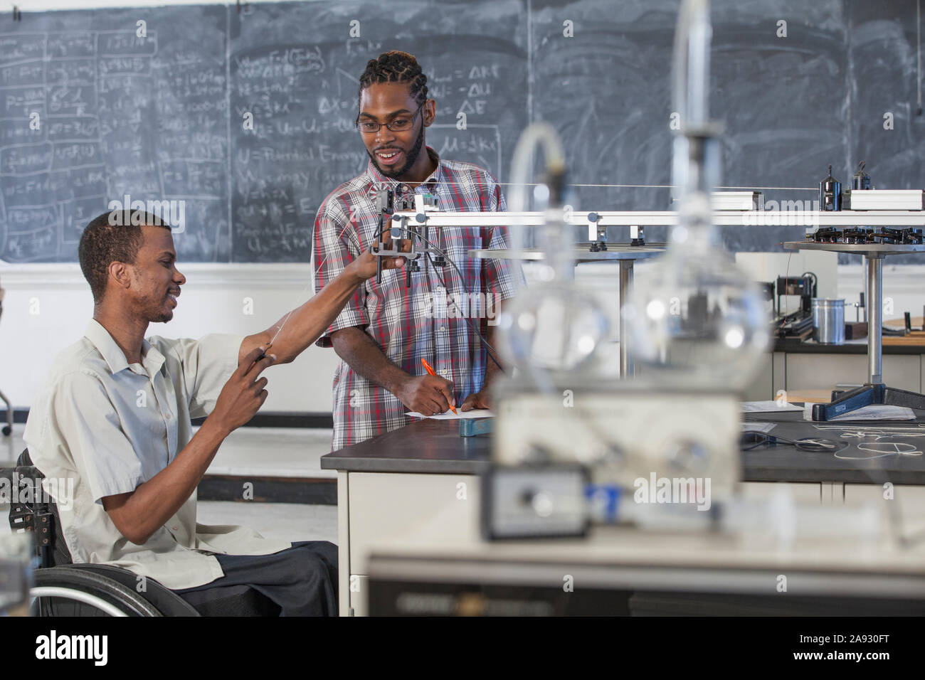 Two students who had Spinal Meningitis studying acceleration on a frictionless table in laboratory Stock Photo