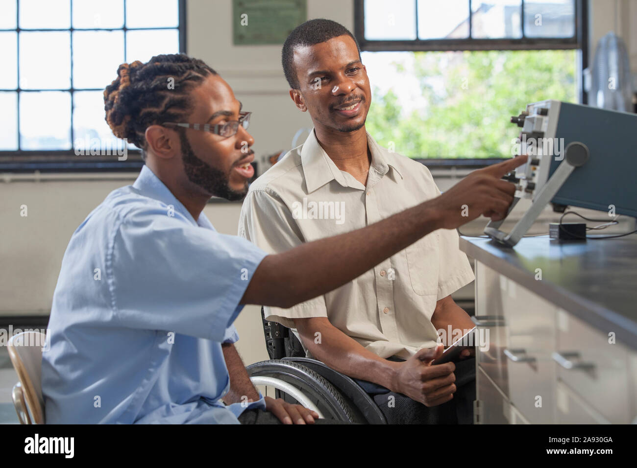 Students who had Spinal Meningitis setting up oscilloscope to use photo detector in laboratory Stock Photo