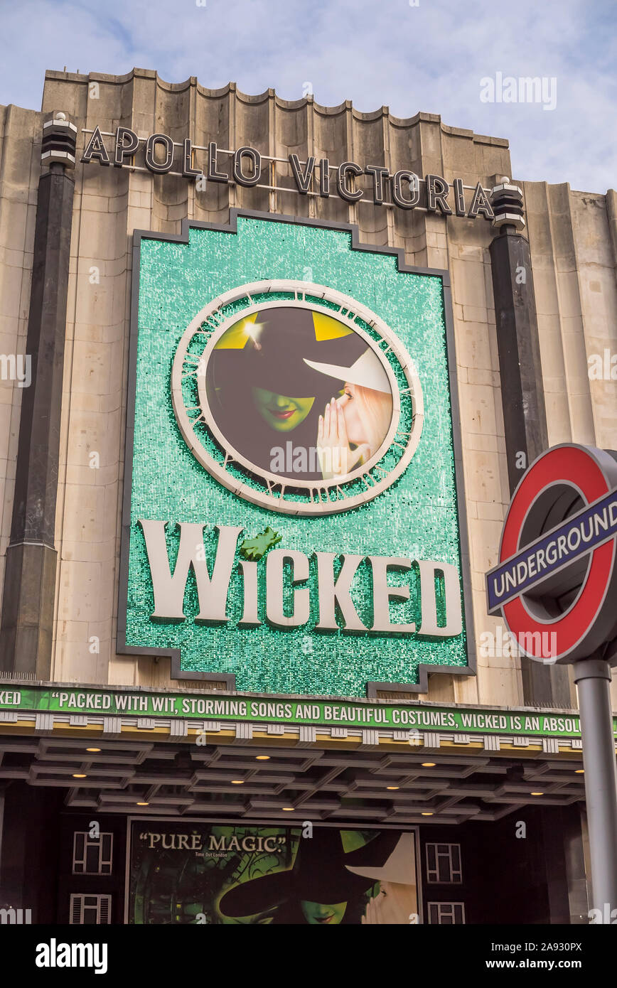 View of Apollo Victoria Theatre London (across from Victoria Station) advertising hit musical production Wicked. London Underground foreground roundel. Stock Photo