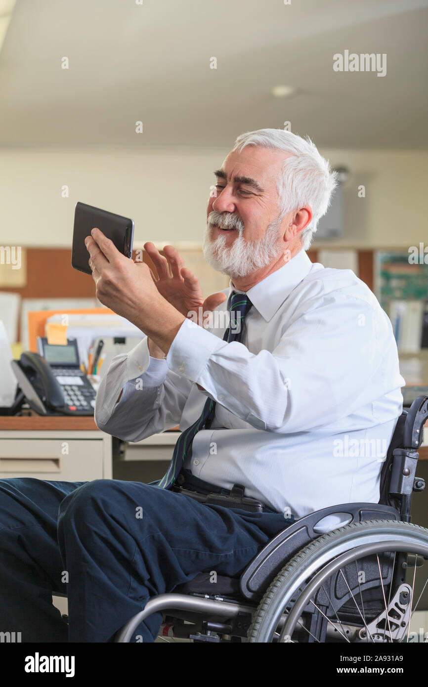Man with Muscular Dystrophy in a wheelchair using a tablet at his