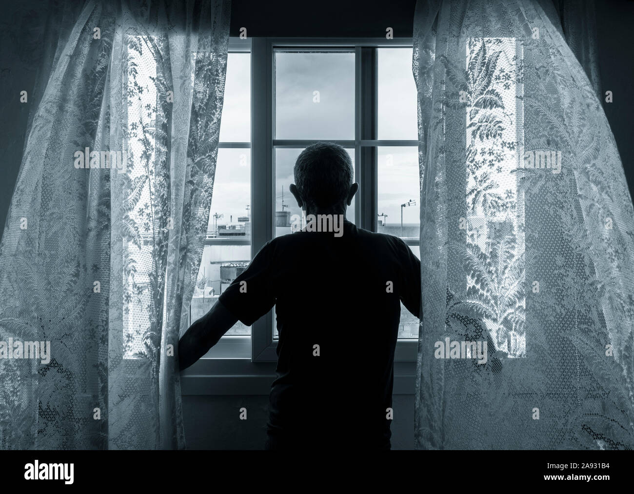 Rear view of man looking out of window. Concept image for depression, male depression, mental health, male suicide... Stock Photo