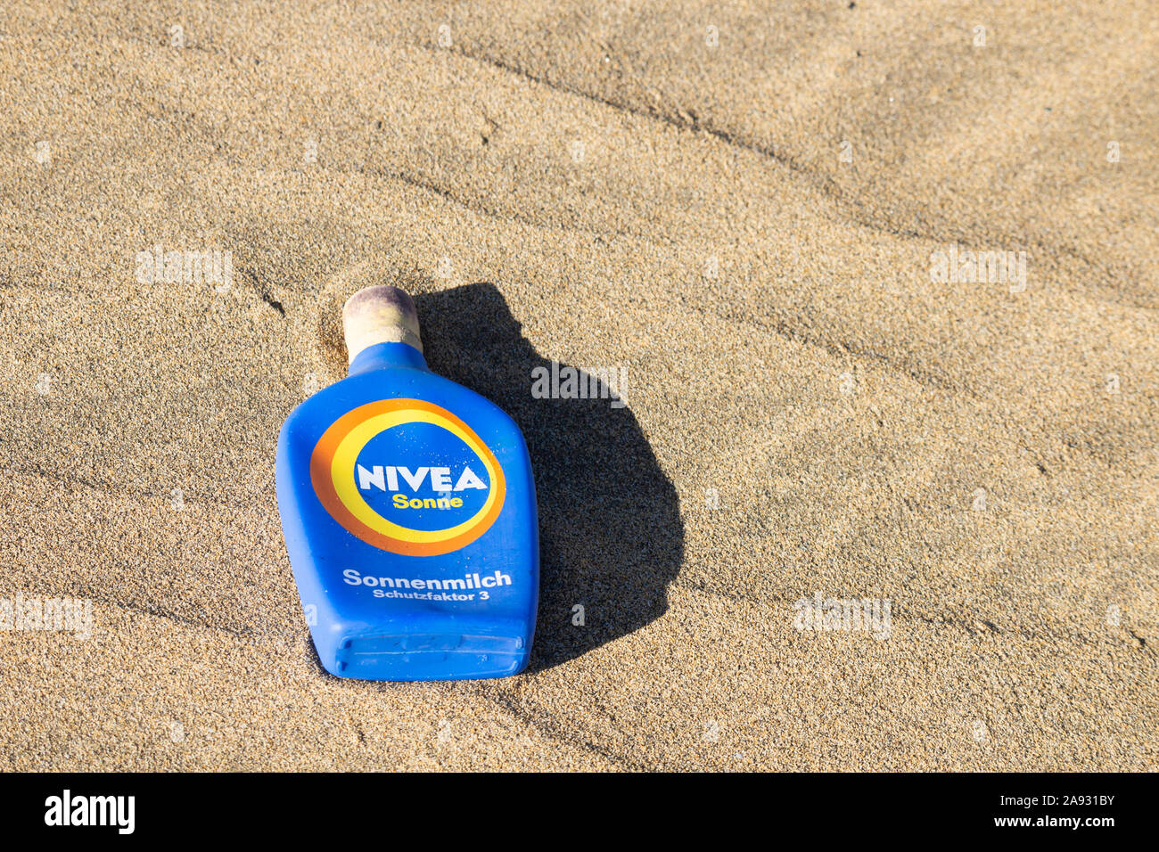 Discarded plastic Nivea suncream bottle on beach in Spain. Stock Photo
