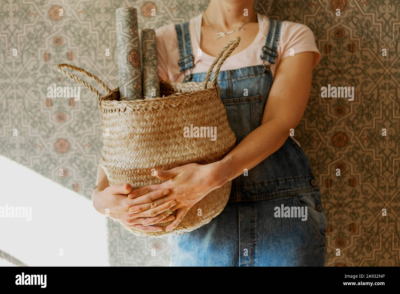 Woman holding basket with wallpaper rolls Stock Photo