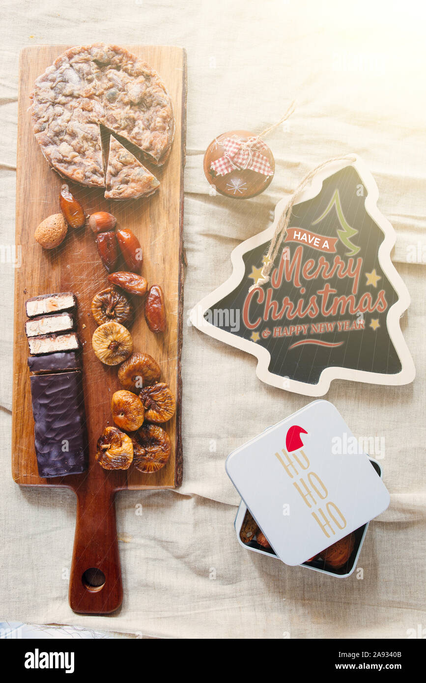 christmas dried dessert on a cutboard, typical italian sweeties offered at the end of christmas dinner,Nougat ,dried fruit ,panforte and dates, top vi Stock Photo