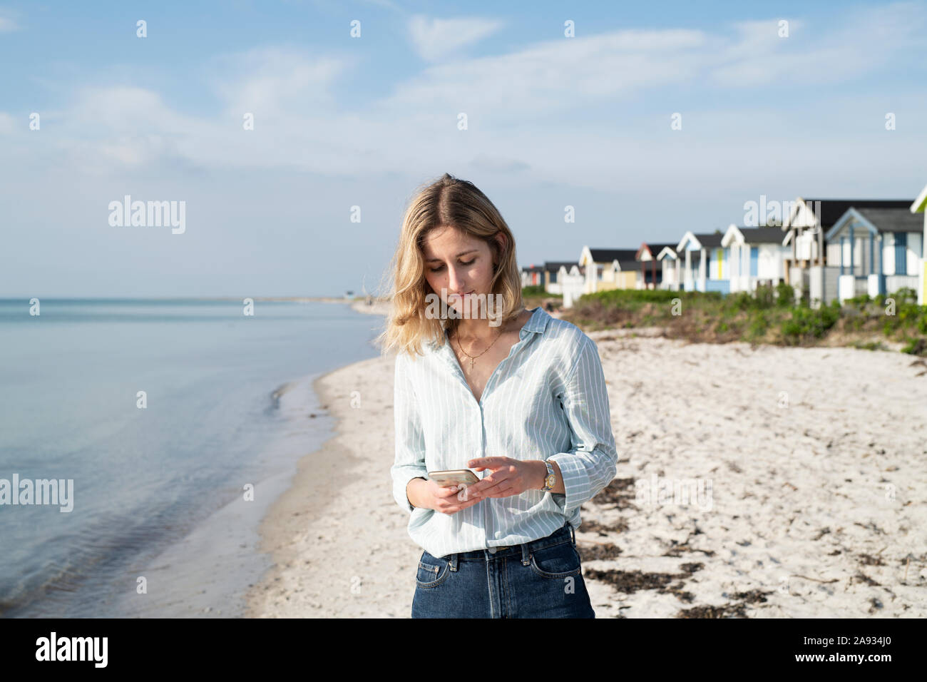 Woman on beach using phone Stock Photo - Alamy