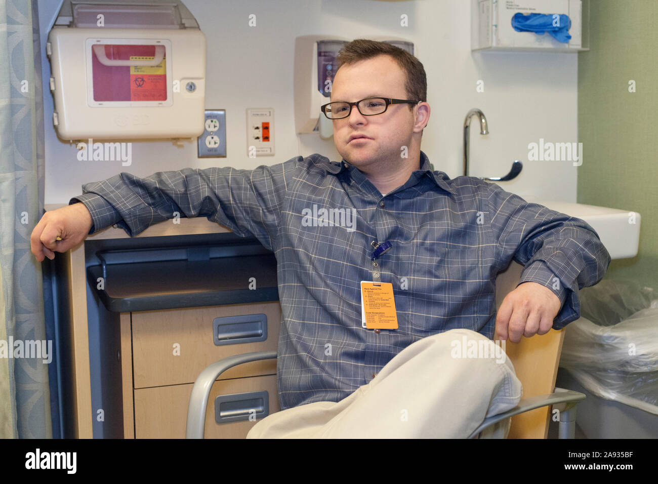 Hospital aid worker with Down Syndrome relaxing at work in office Stock Photo