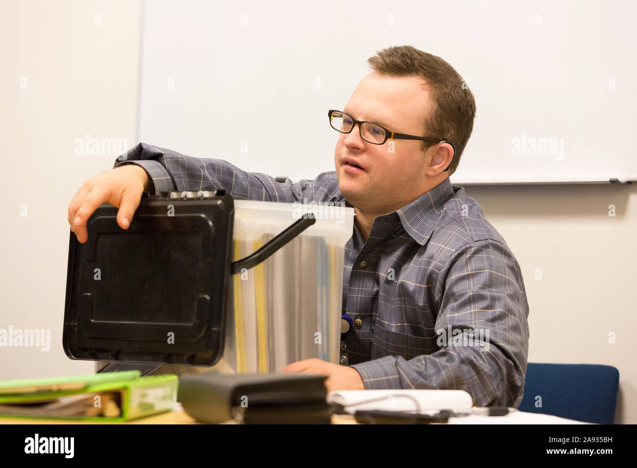 Hospital aid worker with Down Syndrome filing paperwork in office Stock Photo